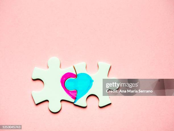 white puzzle pieces with a painted heart on a pink background. heterosexual love concept - ana maria parera bildbanksfoton och bilder