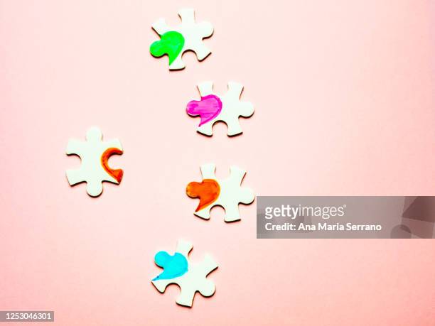 white puzzle pieces with a painted heart on a pink background. polyamory concept - ポリアモリー ストックフォトと画像
