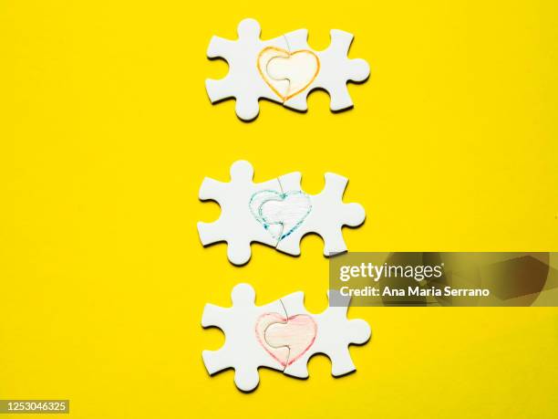 white puzzle pieces with a painted heart on a yellow background - ana maria parera bildbanksfoton och bilder