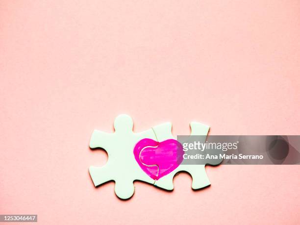 white puzzle pieces with a painted heart on a pink background - ana maria parera bildbanksfoton och bilder