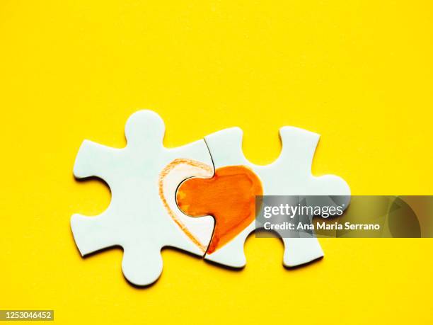 white puzzle pieces with a painted heart on a yellow background - ana maria parera bildbanksfoton och bilder