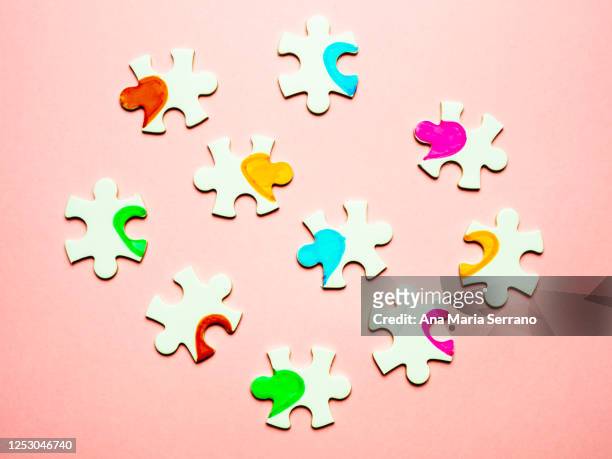 white puzzle pieces with a painted heart on a pink background. polyamory concept - polygamie stock-fotos und bilder