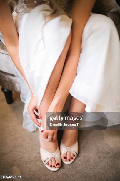 bride putting on her cream coloured high heels - wedding shoes stock pictures, royalty-free photos & images