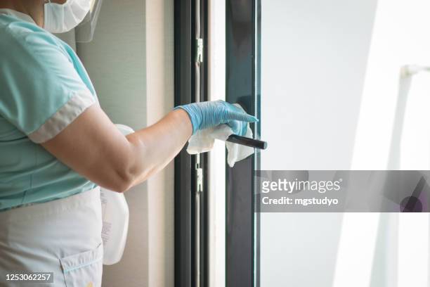 maid cleaning doorknob and wearing a face mask - hospital cleaning stock pictures, royalty-free photos & images