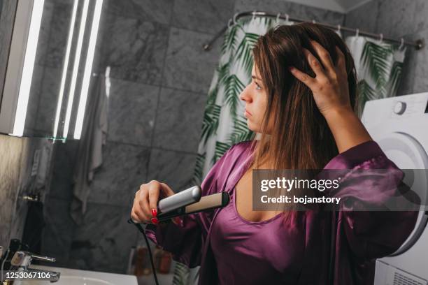 jonge vrouw die haar haar in de badkamers rechttrekt - silk nighty stockfoto's en -beelden