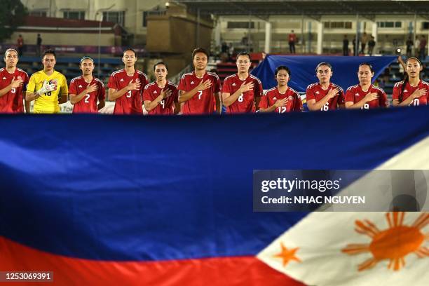 This photograph taken on May 6, 2023 shows Philippines team players sing the national anthem prior to the start of their women's football group match...