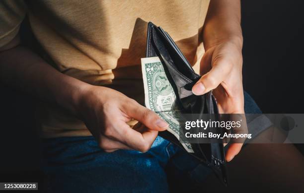 close up of hopeless woman open her empty wallet and found only one dollar bill. - recession foto e immagini stock