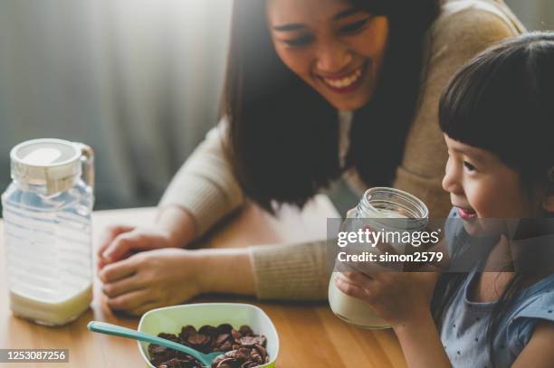 happy young asian mother and her daughter preparing breakfast - milk family stock pictures, royalty-free photos & images