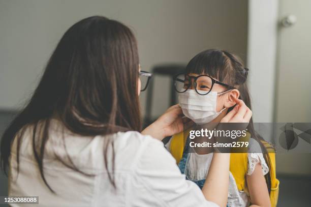 asian mother help her daughter wearing face mask for protection coronavirus outbreak - covid 19 mask stock pictures, royalty-free photos & images