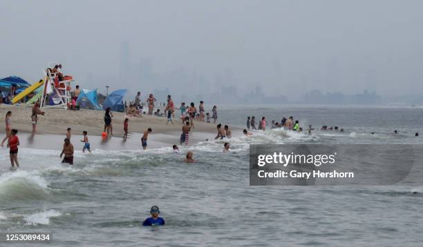 People swim in the Atlantic Ocean in front of the skyline of New York City on a beach at Sandy Hook park at the Jersey Shore on June 27, 2020 in...