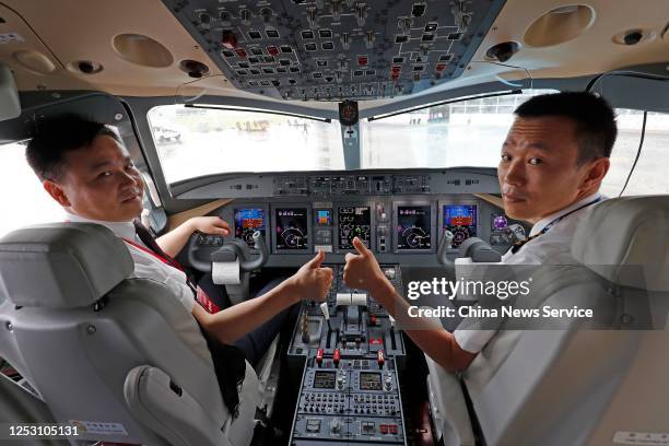 Pilots of China Eastern Airlines pose for photos in its first ARJ21 aircraft, regional passenger jetliner developed and manufactured by the...