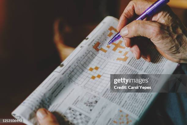 senior man doing crossword on newspaper - korsord bildbanksfoton och bilder