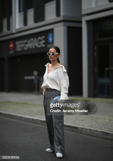 Anna Schürrle wearing Bottega Veneta bag, Alexander Wang blouse, Max Mara pants, Tiger sneaker and Celine shades on June 28, 2020 in Berlin, Germany.