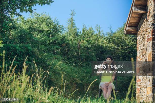 mujer tomando una taza de cafe o te en su jardin - taza cafe stock pictures, royalty-free photos & images