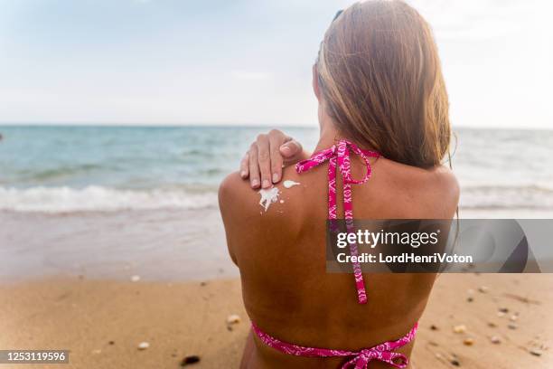 kvinna som applicerar sollotion på ryggen för att skydda hennes hud - cancerland 2019 bildbanksfoton och bilder