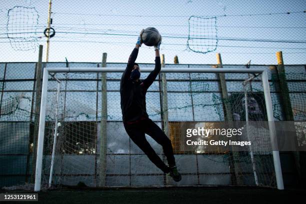 Andres Herniaga catches the ball while playing an informal football match in a field with lines marked to keep distance on June 27, 2020 in...
