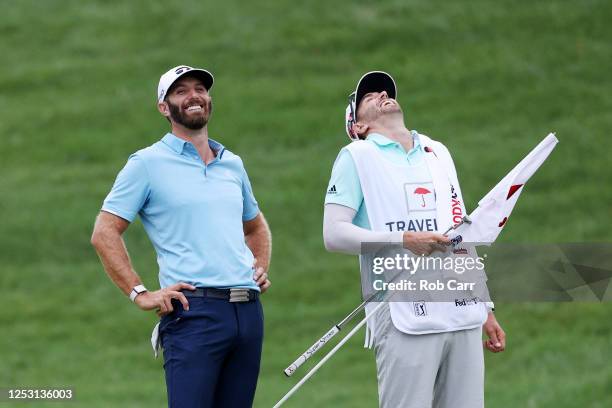 Dustin Johnson of the United States reacts with caddie Austin Johnson after making a putt for par on the 18th green to win the Travelers Championship...