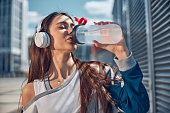 Sportswoman in headphones holding a plastic bottle