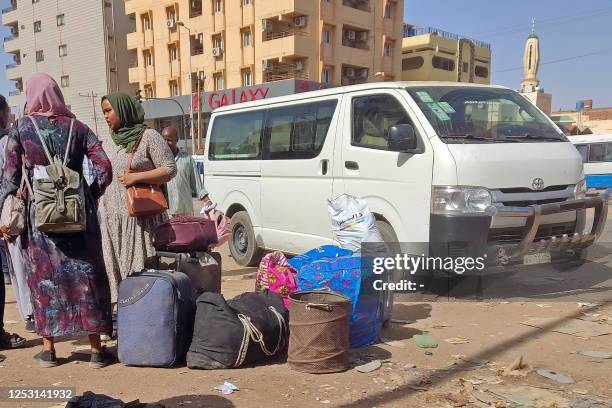 People wait with their luggage at a bus stop in southern Khartoum on May 8, 2023 as fighting continues between Sudan's army and the paramilitary...