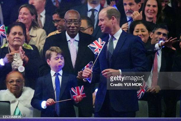 Britain's Prince George of Wales reacts as his father Britain's Prince William, Prince of Wales plays with a Union flag during the Coronation Concert...
