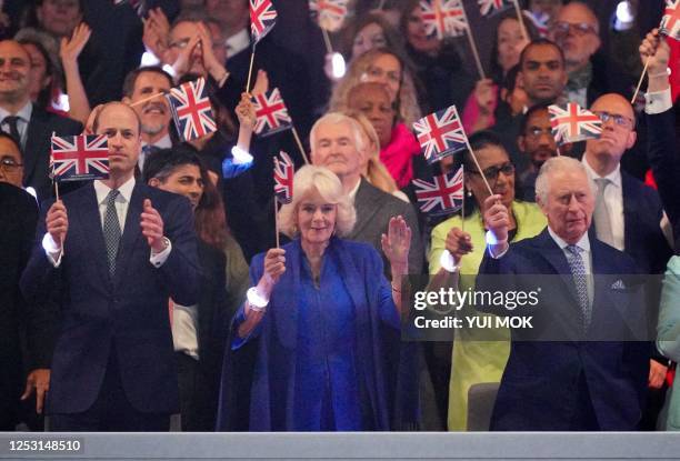 Britain's Prince William, Prince of Wales , Britain's Queen Camilla and Britain's King Charles III wave Union flags during the Coronation Concert at...