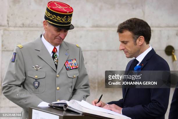 French President Emmanuel Macron signs a registry book at the tomb of the unknown soldier at the Arc de Triomphe as he attends the ceremonies marking...