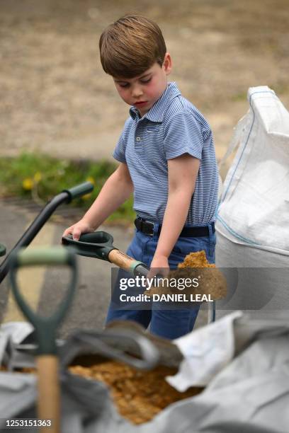 Britain's Prince Louis of Wales helps his parents as they take part in the Big Help Out, during a visit to the 3rd Upton Scouts Hut in Slough, west...