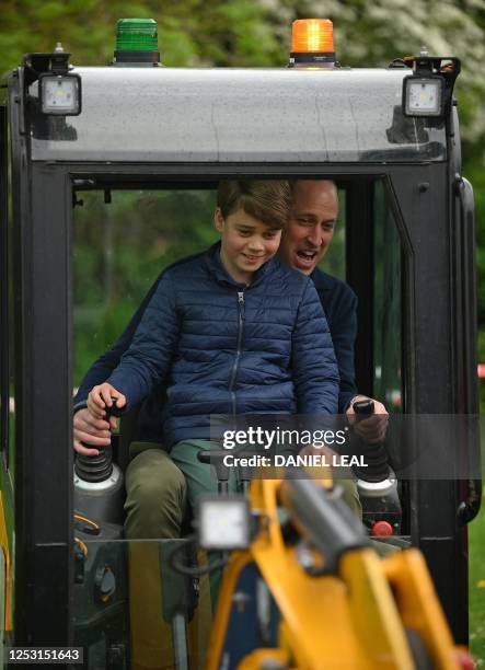 Britain's Prince William, Prince of Wales is helped by Britain's Prince George of Wales as he uses an excavator while taking part in the Big Help...