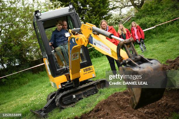 Britain's Prince William, Prince of Wales is helped by Britain's Prince George of Wales as he uses an excavator while taking part in the Big Help...