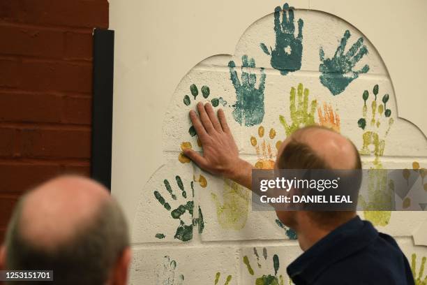 Britain's Prince William, Prince of Wales uses his hand to make a paint decorations on a wall while taking part in the Big Help Out, during a visit...
