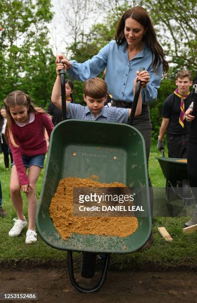 Britain's Prince Louis of Wales takes control of a wheelbarrow as he helps his mother, Britain's Catherine, Princess of Wales and sister Britain's...