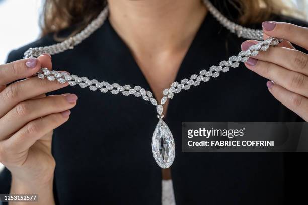 This photograph taken on May 8 shows an employee of Christie's auction house holding the "Briolette of India" a 90.36 carats colourless diamond, a...