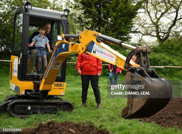 Britain's Prince William, Prince of Wales is helped by Britain's Prince Louis of Wales as he uses an excavator while taking part in the Big Help Out,...