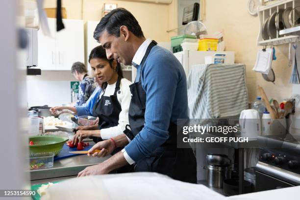 Britain's Prime Minister Rishi Sunak and his wife Akshata Murty help out in the kitchen as they take part in the Big Help Out, during a visit to a...