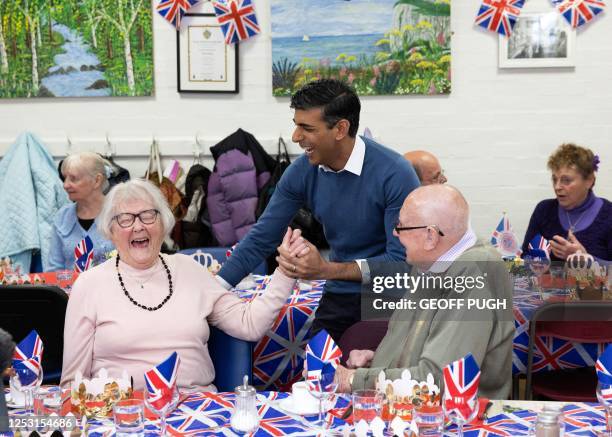 Britain's Prime Minister Rishi Sunak chats with people as he and and his wife Akshata Murty take part in the Big Help Out, during a visit to a lunch...