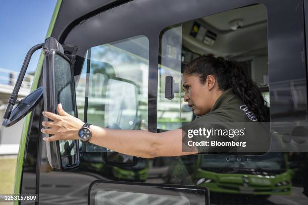 Bus driver adjusts a side view mirror on a La Rolita electric bus at the Perdomo depot in the Ciudad Bolivar neighborhood of Bogota, Colombia, on...