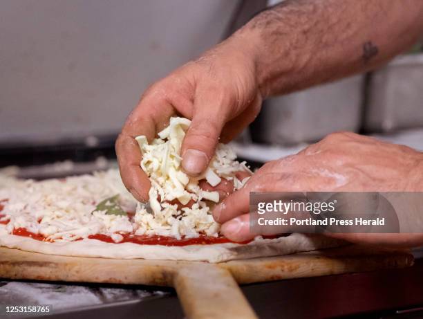 Francesco Coletti puts mozzarella cheese on a pizza at his Biddeford pizza restaurant, Coletti's Pizza Factory, on Wednesday, April 5, 2023. Coletti...