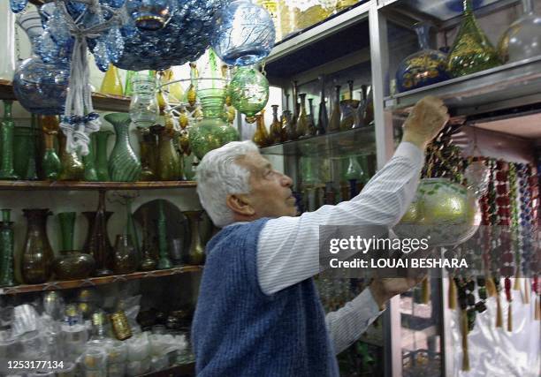 Hassan al-Kazzazi hangs up a vase at his shop in Damascus 13 May 2001. Hassan's glassblowing workshop was built in the 16th century under the Ottoman...