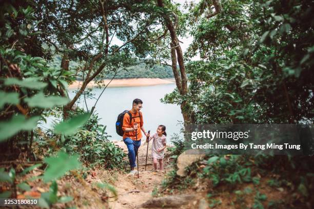 young asian dad & lovely daughter hiking together joyfully on woodland trail with hiking poles - asian young family bildbanksfoton och bilder