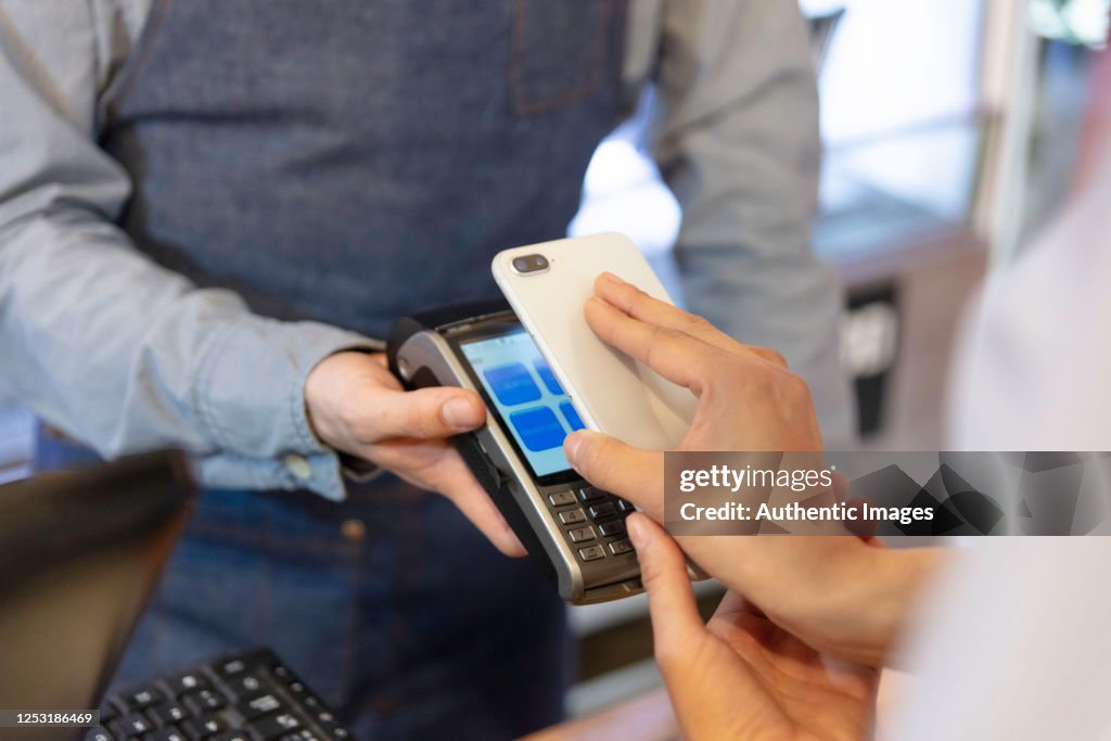 Female customer paying to bar's owner