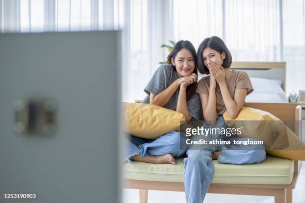 students - two female teenager watching television at the hostel on holiday trip. - asian watching movie stockfoto's en -beelden