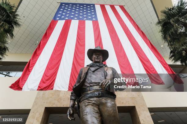 Statue of John Wayne is on display beneath an American flag in John Wayne Airport, located in Orange County, on June 28, 2020 in Santa Ana,...