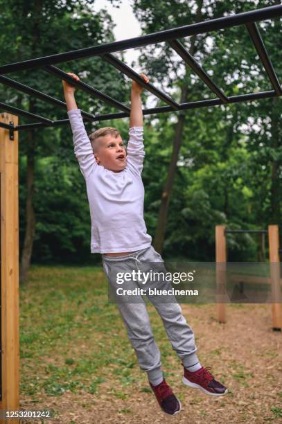 boy swinging on monkey bars - boy on monkey bars stock pictures, royalty-free photos & images