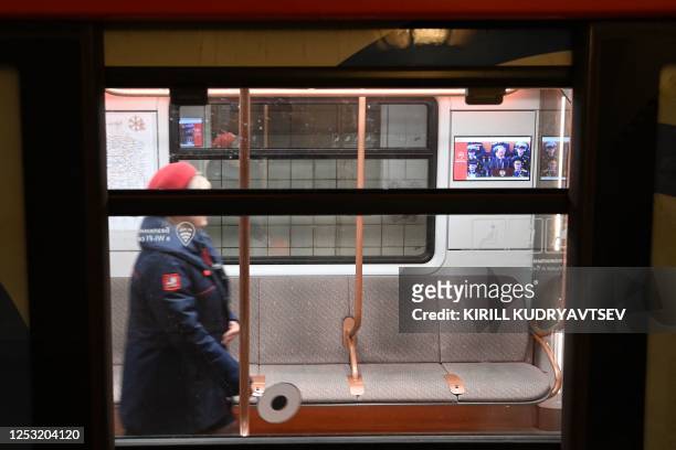 Metro employee walks along a metro coach as a screen shows a live broadcast of the Victory Day military parade from Red Square, in Moscow on May 9,...