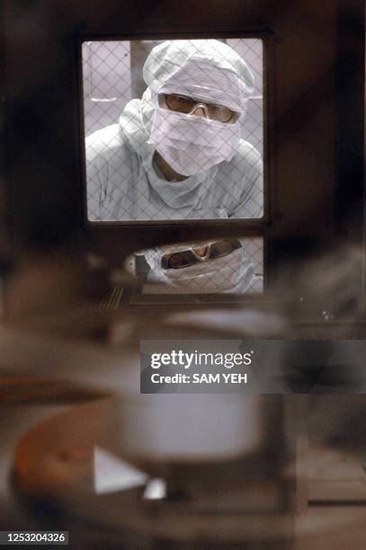 An engineer of United Microelectronics Corp checks a wafer inside a machine at the company's wafer factory in Tainan Science Park, southern Taiwan,...