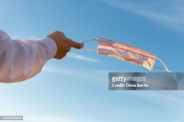 low angle view of hand holding mask against sky - the end stock pictures, royalty-free photos & images
