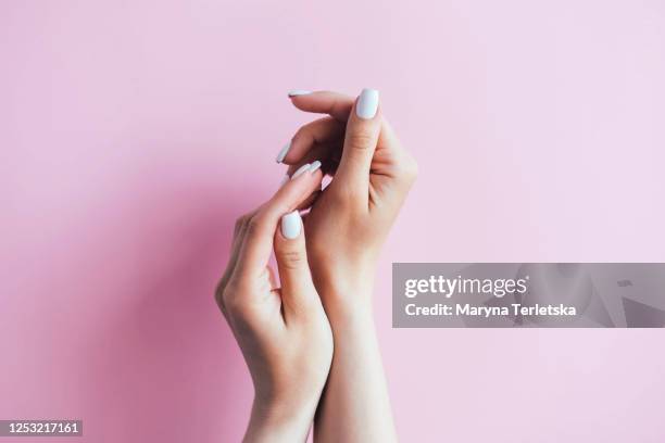 female hands with white manicure on a pink background. - manicure stockfoto's en -beelden
