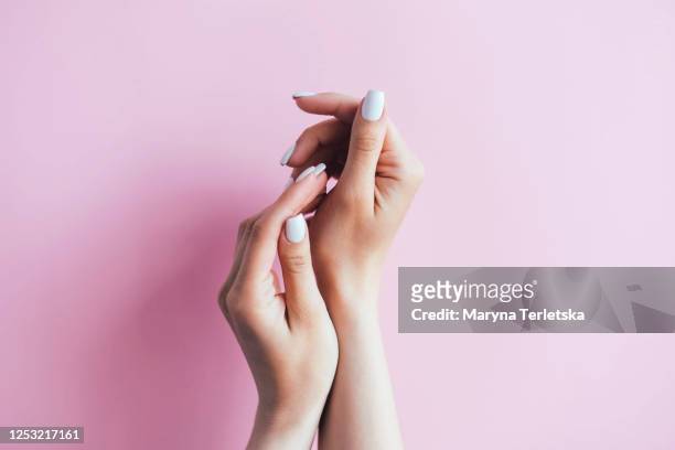 female hands with white manicure on a pink background. - manicured hands stock pictures, royalty-free photos & images