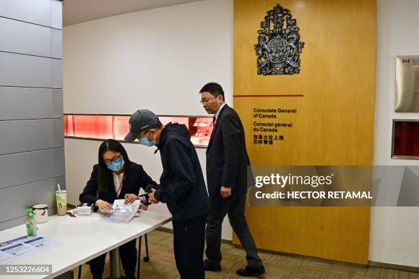 Worker at the Consulate General of Canada tends to a man at the entrance of the consulate in Shanghai on May 9, 2023. - China said May 9 it was...