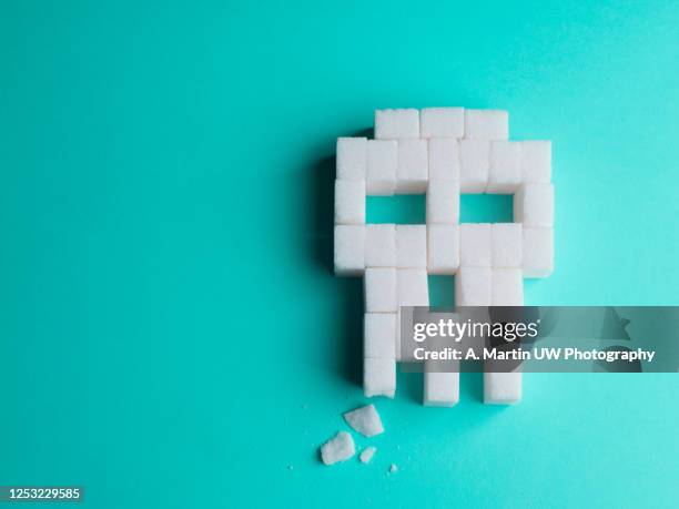skull made of sugar cubes with a broken tooth. concept of tooth decay. - zucker stock-fotos und bilder